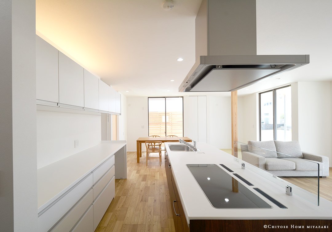 キッチン収納の上部に設えた間接照明がLDKのフラットな天井空間を印象的に演出する。