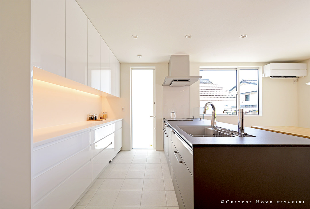 床をタイル張り仕上げにしたオープンキッチンには、間接照明で光と影を演出。シンプルで規則的なデザインの機能美溢れるキッチン空間。