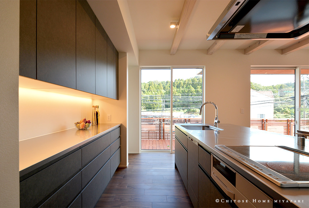 東面からの光を採り込むキッチン空間。キッチン本体と、間接照明を設えたカップボードの天板をステンレス素材で統一。高級感のあるキッチン空間に。