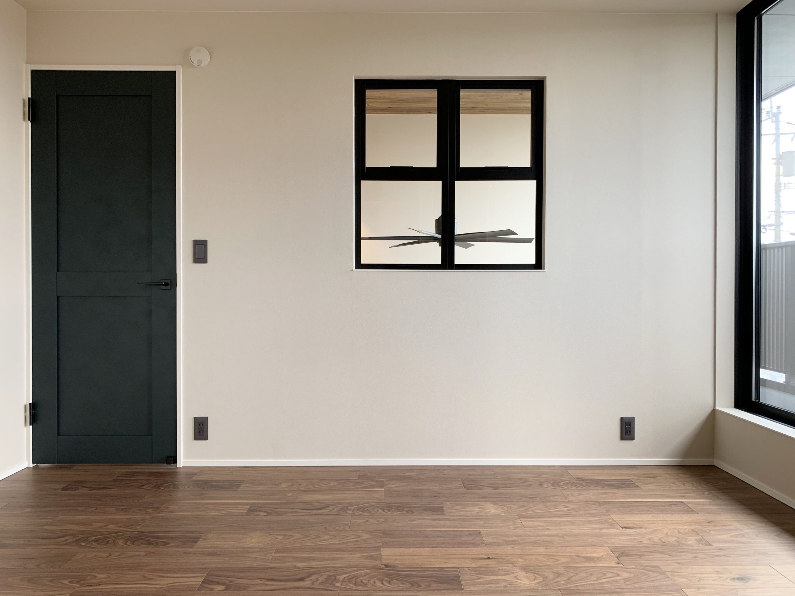 2階寝室と吹き抜けを繋ぐ室内窓。室内ドアとウォルナット床材、鋳鉄調の窓枠に、共通したマットな質感を採り入れる。