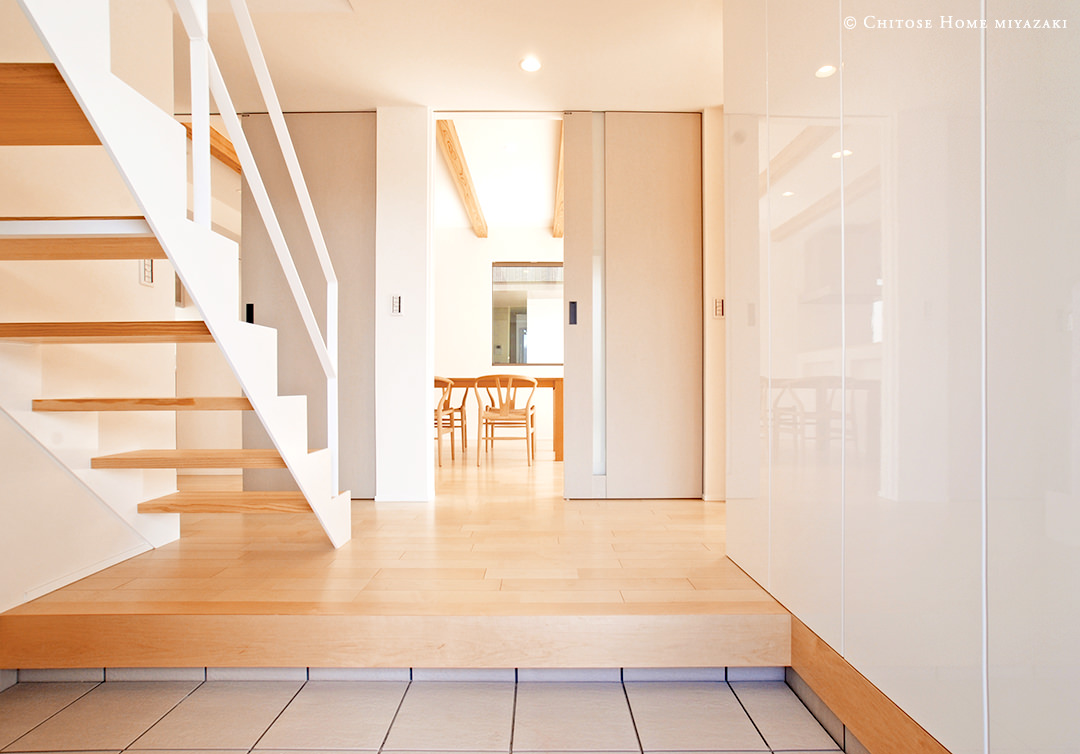 オープン階段にする事で、玄関の幅を広く見せる事が可能に。同じ面積を使った時にでも、拡がり感を生み出すような空間設計に。マイルドな木目の床材をチョイスする事で、上質な印象に。