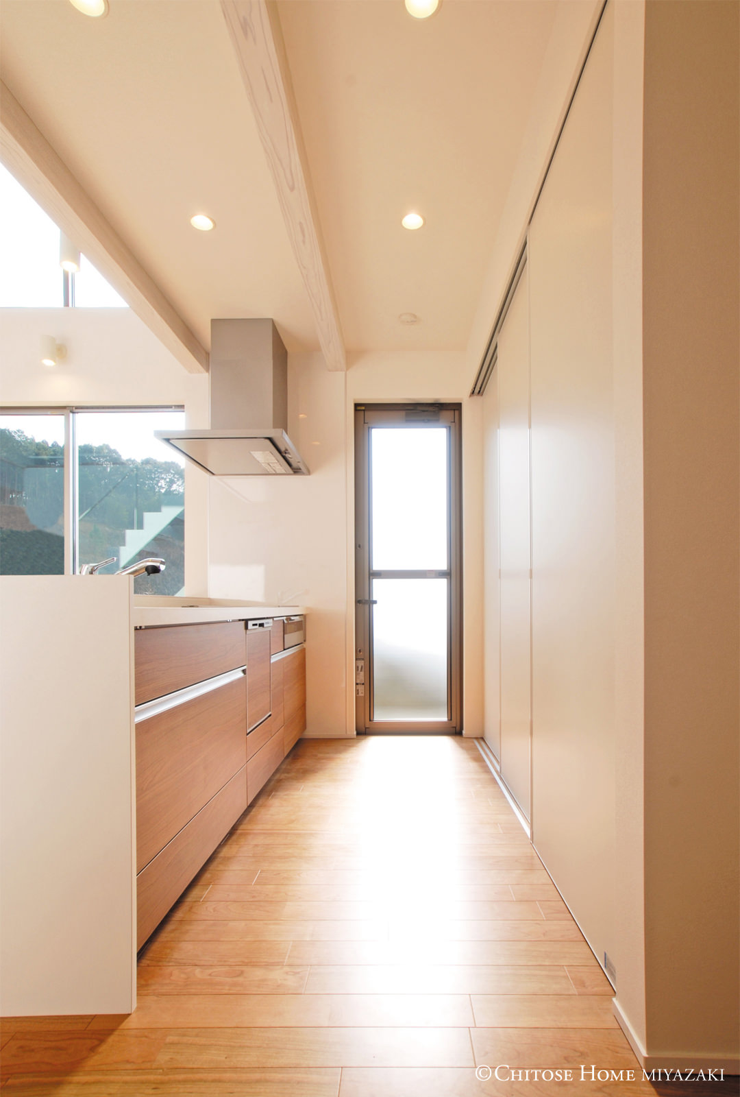 キッチン後部の収納は、パーテーション扉で食器棚を隠せるように。来客時には生活感のあるスペースを見せないように工夫。収納や扉、窓の高さを揃えることも、拡がりの演出の一環。