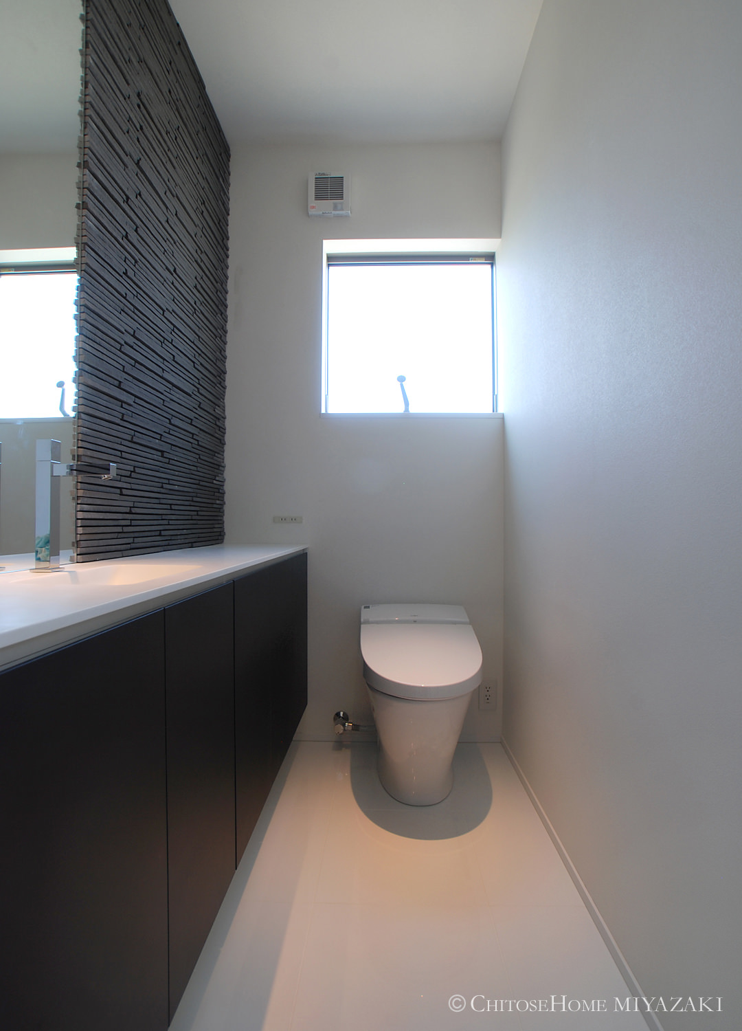 トイレ空間には、鏡面仕上げのタイル床材と、凹凸感のある石目調壁タイルを使用。来客時にもプレミアム感のある個室を使用して頂けるよう配慮。