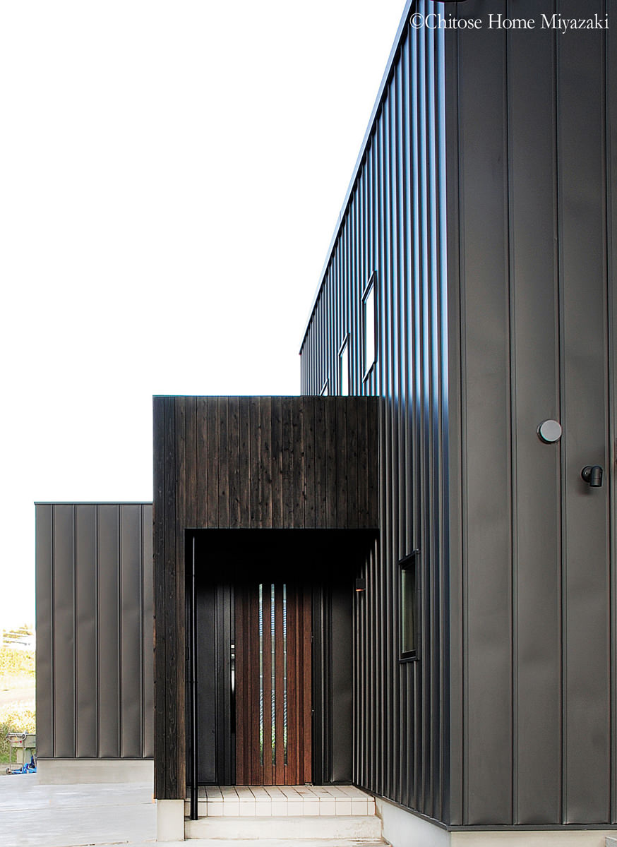 存在感のあるブラックのガルバニュウム鋼板の建物本体に、杉板貼りの玄関ホールを隣接。箱型の形状の組み合わせが、彫りの深い表情と、奥行き感のある外観デザインを構成している。