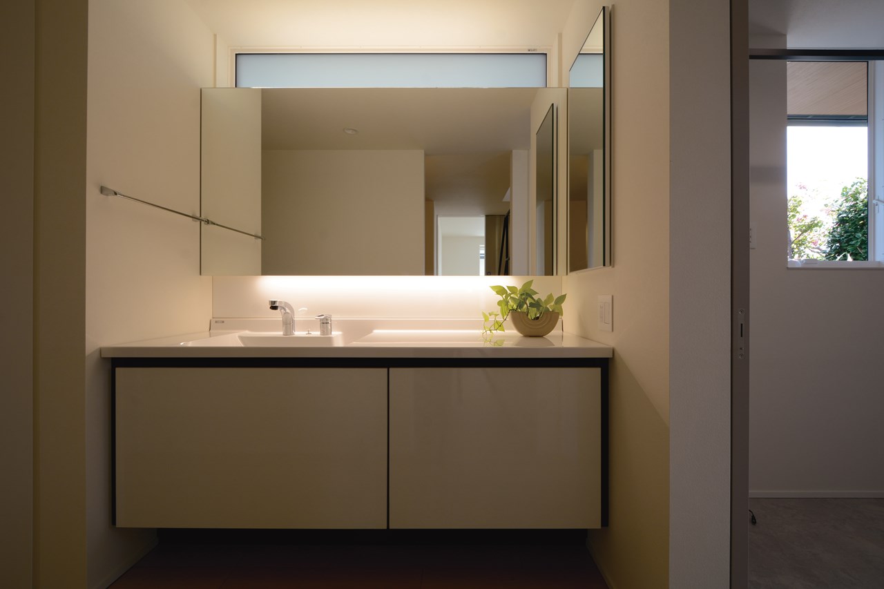 脱衣室とセパレートして、ホテルライクな質感を実現したセミオーダーの洗面スペース。北側の高窓から柔らかな間接光を採り込む。