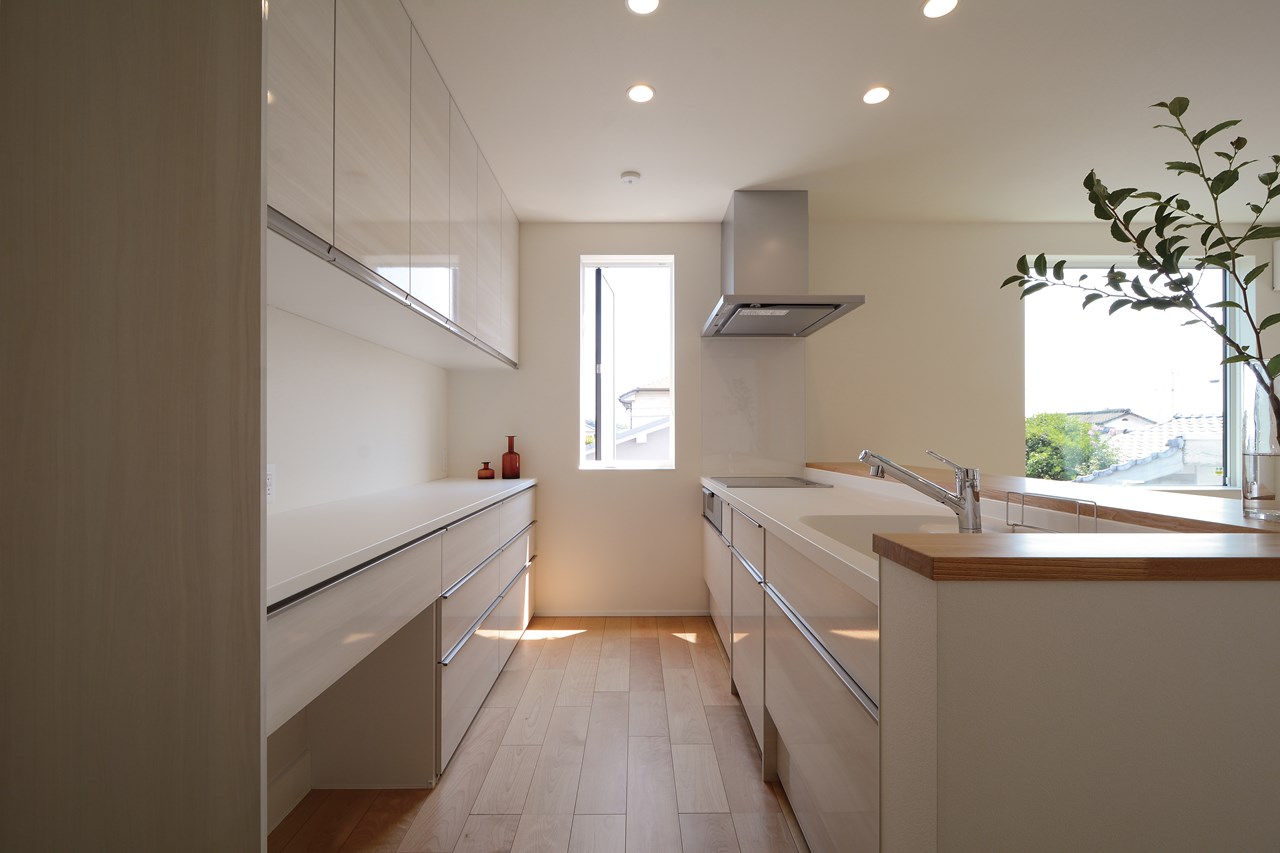 LDK全体を見渡せる配置にキッチンを据え、サイドには階段下のデッドスペースを利用したパントリー収納を確保。キッチンの横に設けた風通しに優れた形状の窓から、炊事の時間を快適なものにする。
