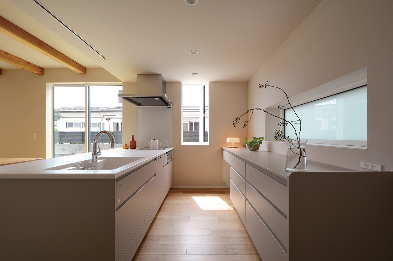 Ｊ型取手のノイズレスな扉を使ったキッチンは、すっきりとシンプルなミニマムデザインに。幅2.7ｍのカウンター収納の他にもパントリー小部屋を設け、機能的で収納力のあるキッチン周辺の使い勝手を実現。