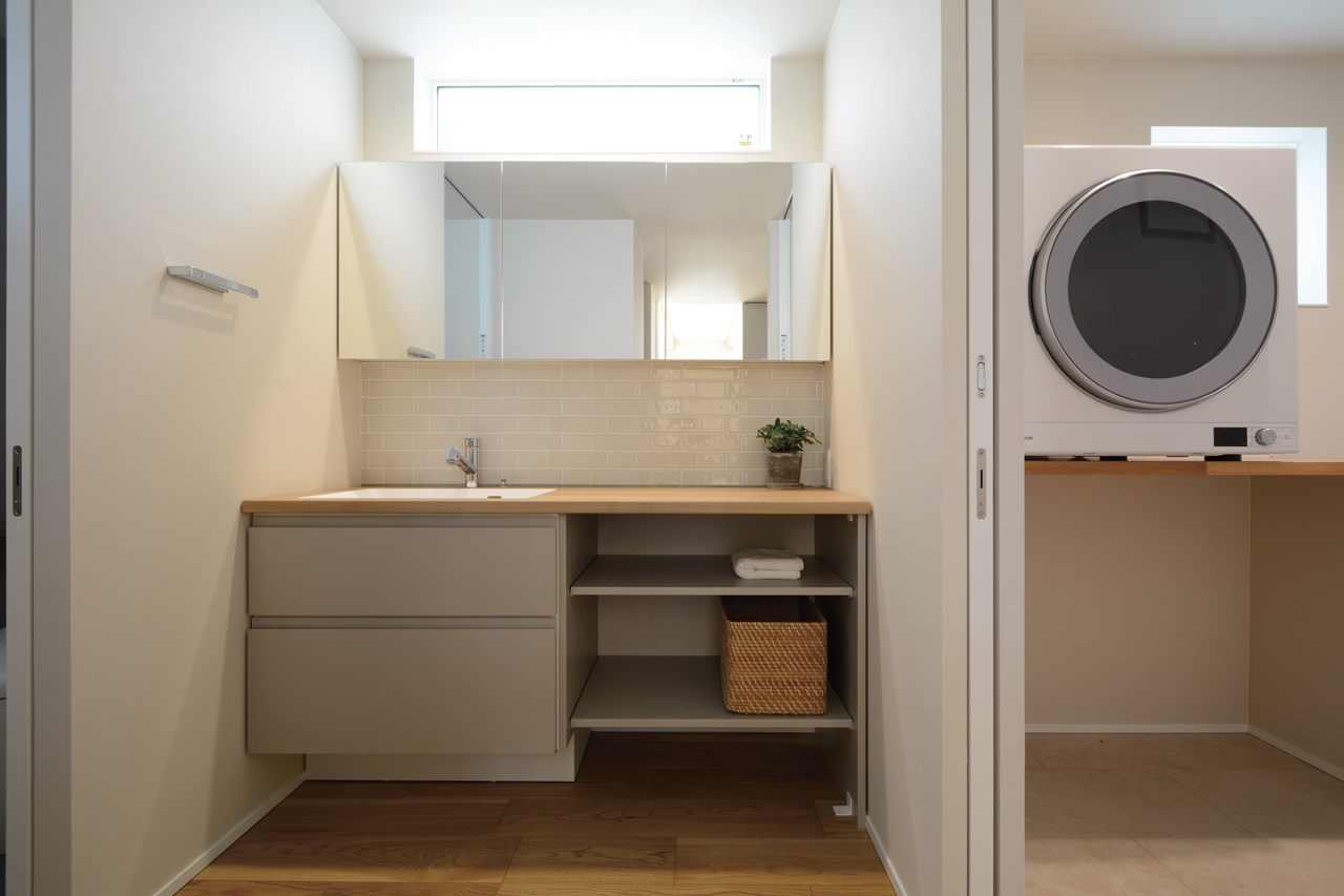 洗面コーナーと脱衣室を分けた間取りに。上質感を演出したセミオーダー洗面台と隔てる形で、家事の時短を見据えた物干ランドリー脱衣室には十分な収納スペースを設ける。