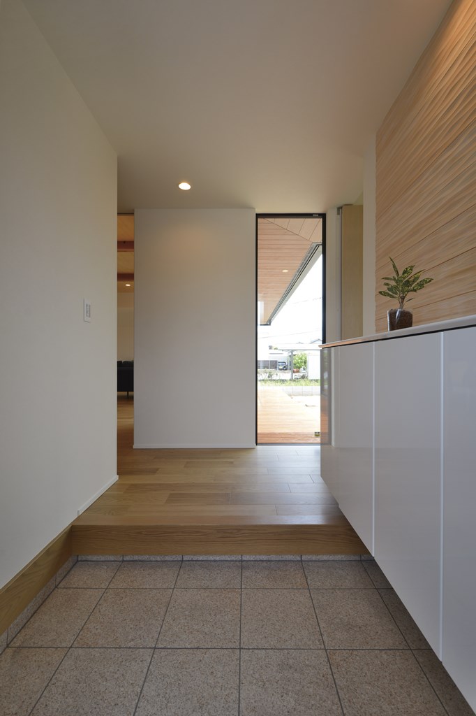 玄関ホールの正面に、床から天井までのFIX窓を設え、抜け感を出す。御影石の土間仕上げや、名栗加工を施した杉材の壁仕上げで上質感を演出。