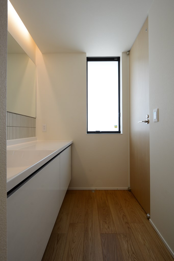 タイル張り仕上げと間接照明を設えた、セミオーダーの洗面コーナー。北側窓から柔らかな自然光と風を採り込む。