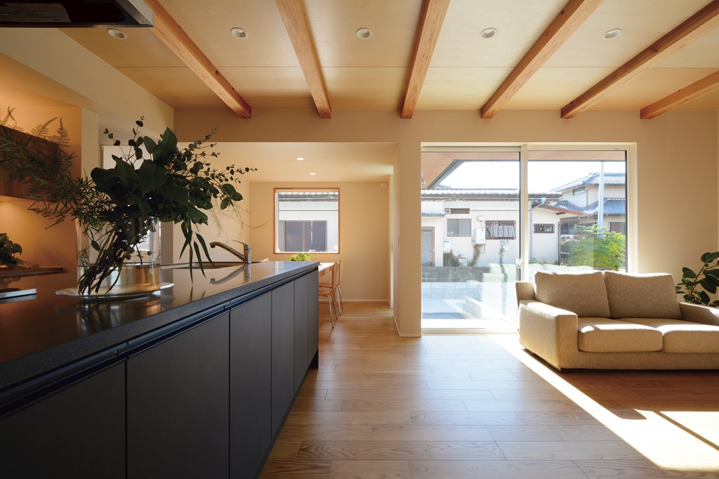 天井には上質な木板張りを施し、素材感が際立つLDK空間に。幅2.5ｍの大開口サッシからは冬のぽかぽかとした陽射しが差し込み、タイルデッキというウチとソトの中間領域へと、ゆるやかに空間がつながる。