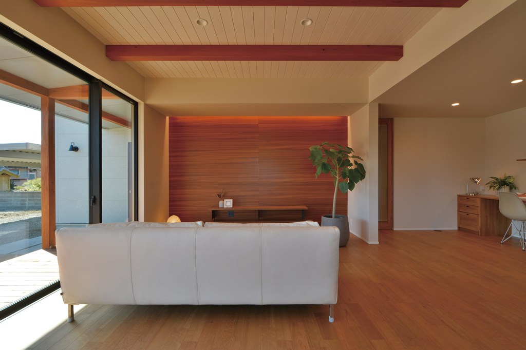 間接照明を設えたＴＶ台背面の壁には木目パネルを採用し、チェリーの床材や板張り天井仕上げとトータルでコーディネート。ソファサイドに十分なゆとりを持たせた設計。